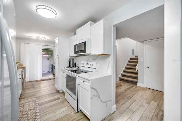 kitchen with light stone counters, light wood finished floors, white range with electric stovetop, and white cabinets