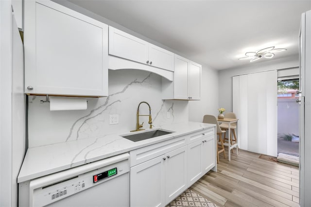 kitchen featuring light wood-style floors, white cabinetry, white dishwasher, and a sink