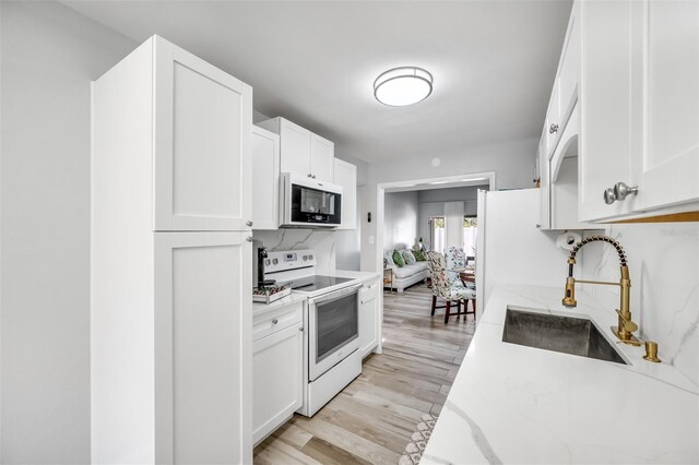 kitchen with light stone counters, white electric range, a sink, white cabinetry, and light wood-style floors