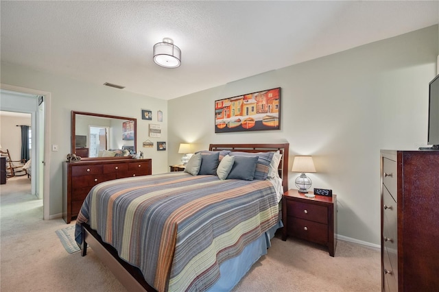 bedroom featuring light carpet and a textured ceiling