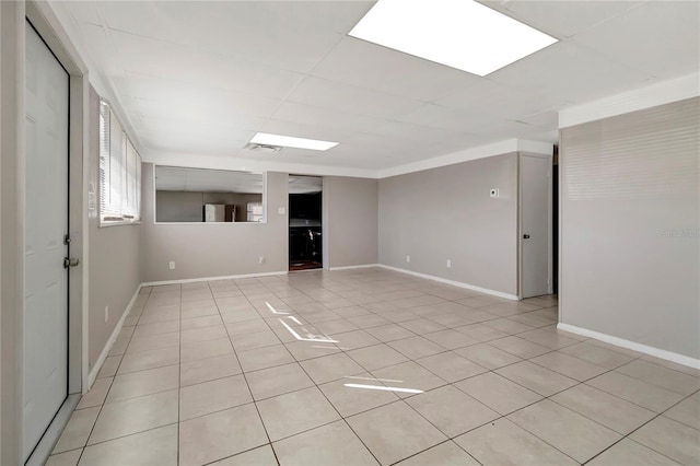 unfurnished room with a drop ceiling and light tile patterned floors