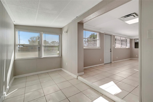 tiled empty room featuring a drop ceiling