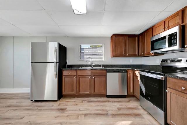 kitchen featuring a paneled ceiling, stainless steel appliances, light hardwood / wood-style floors, and sink