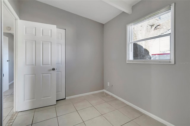 tiled empty room with beamed ceiling