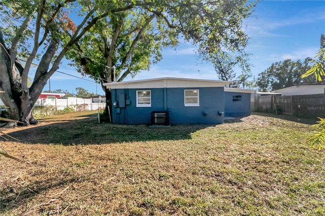 back of property with a yard and central AC