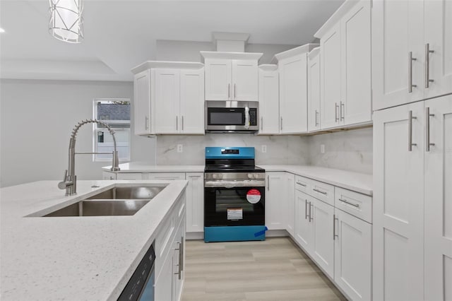 kitchen with sink, light hardwood / wood-style floors, decorative light fixtures, white cabinets, and appliances with stainless steel finishes