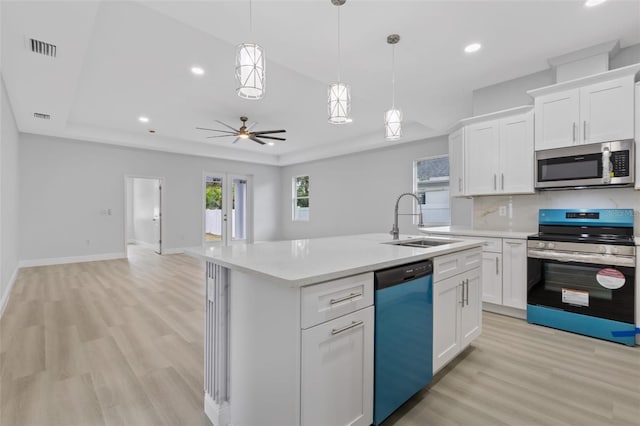 kitchen with white cabinets, a center island with sink, sink, ceiling fan, and appliances with stainless steel finishes