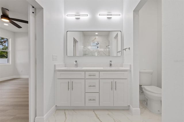 bathroom featuring vanity, ceiling fan, toilet, tiled shower, and wood-type flooring