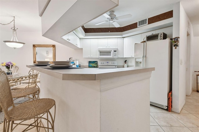 kitchen featuring hanging light fixtures, white cabinets, kitchen peninsula, white appliances, and light tile patterned floors