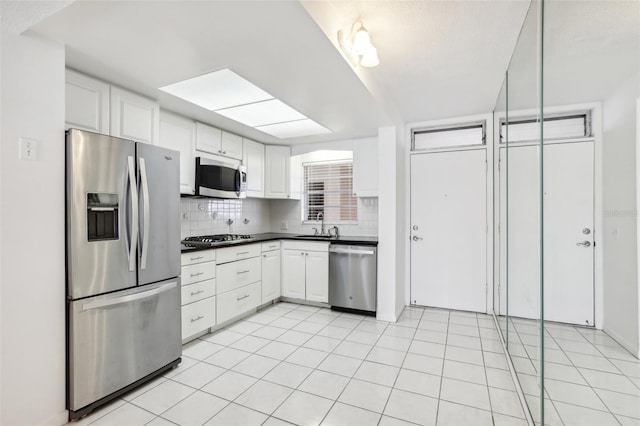 kitchen with sink, light tile patterned floors, backsplash, white cabinets, and appliances with stainless steel finishes