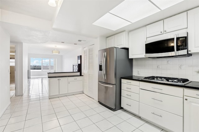 kitchen featuring appliances with stainless steel finishes, backsplash, white cabinetry, and light tile patterned floors