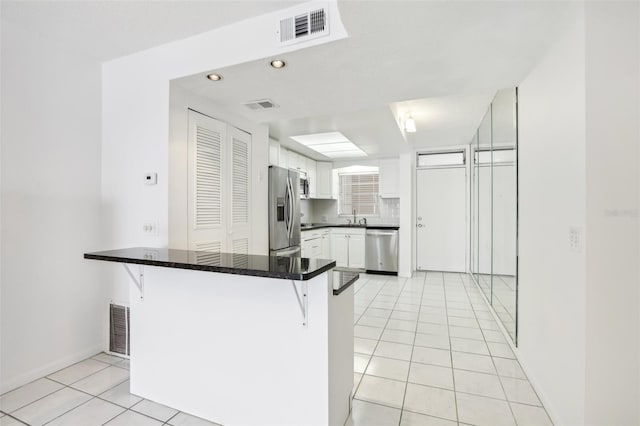 kitchen featuring white cabinets, a kitchen breakfast bar, stainless steel appliances, and kitchen peninsula