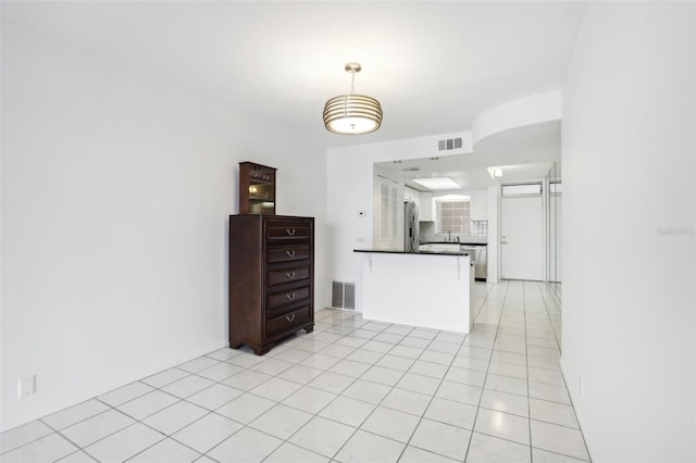 kitchen featuring kitchen peninsula, decorative backsplash, light tile patterned flooring, and stainless steel refrigerator with ice dispenser