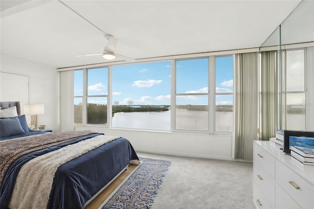 carpeted bedroom with ceiling fan and a water view