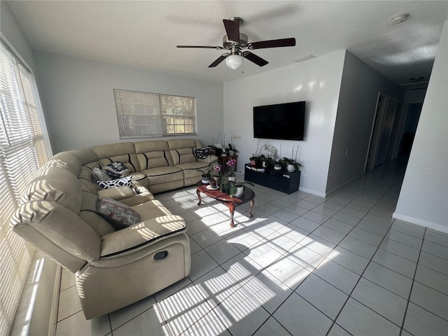 tiled living room featuring ceiling fan, a healthy amount of sunlight, and a textured ceiling