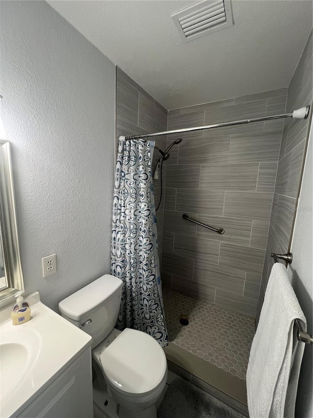 bathroom featuring a shower with shower curtain, a textured ceiling, vanity, and toilet