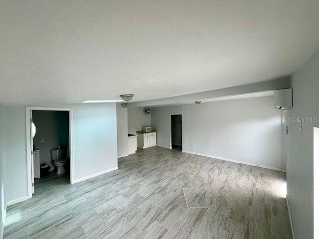 spare room featuring a textured ceiling and light hardwood / wood-style floors