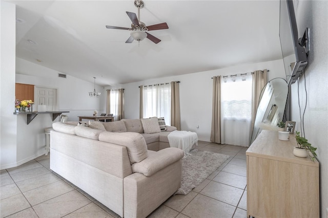 tiled living room featuring ceiling fan with notable chandelier, a healthy amount of sunlight, and vaulted ceiling