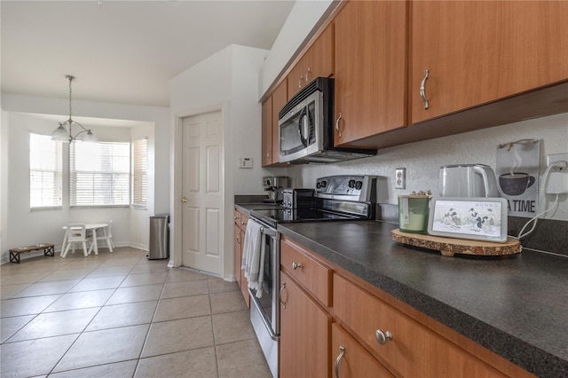 kitchen with an inviting chandelier, hanging light fixtures, vaulted ceiling, appliances with stainless steel finishes, and light tile patterned flooring