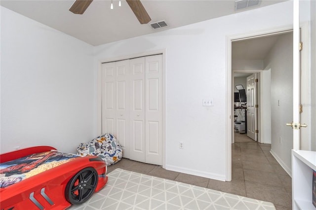 tiled bedroom with ceiling fan and a closet