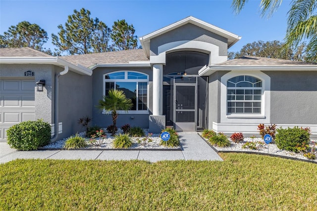 view of exterior entry featuring a garage and a yard