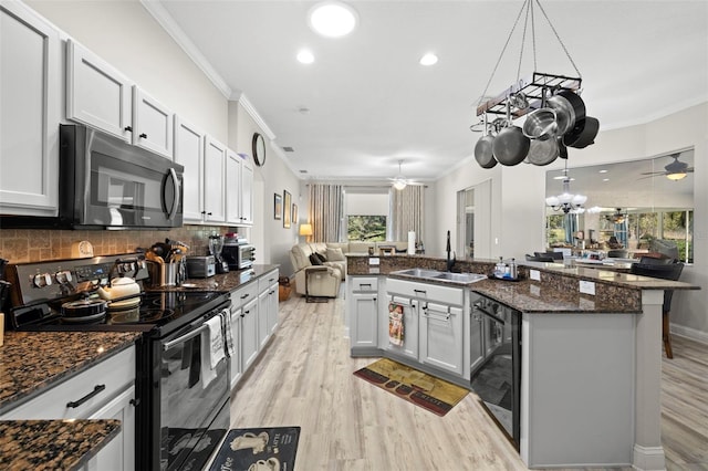 kitchen featuring sink, stainless steel appliances, hanging light fixtures, and dark stone counters