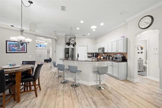 kitchen with pendant lighting, a breakfast bar area, tasteful backsplash, white cabinetry, and stainless steel appliances