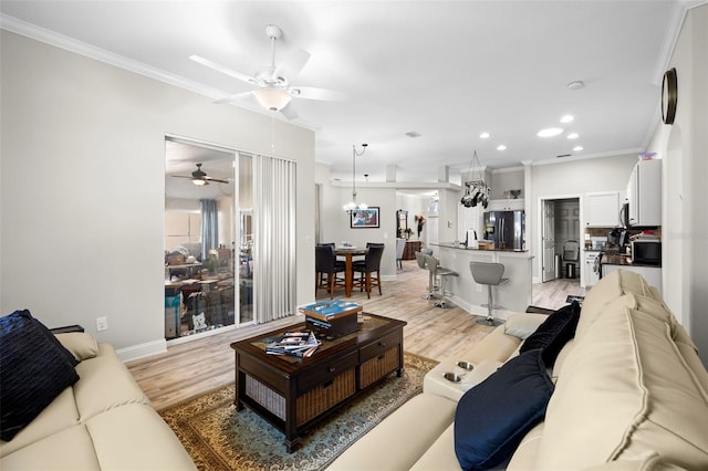 living room with ceiling fan, light wood-type flooring, and crown molding