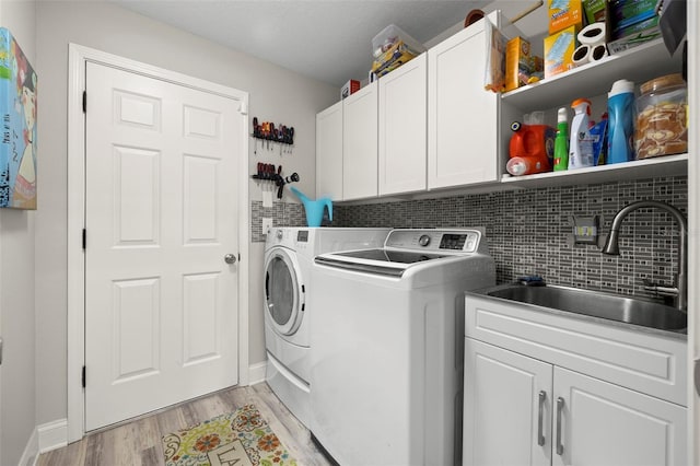 laundry room with sink, cabinets, independent washer and dryer, light hardwood / wood-style floors, and a textured ceiling