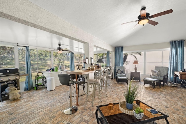 sunroom featuring ceiling fan, a healthy amount of sunlight, and lofted ceiling