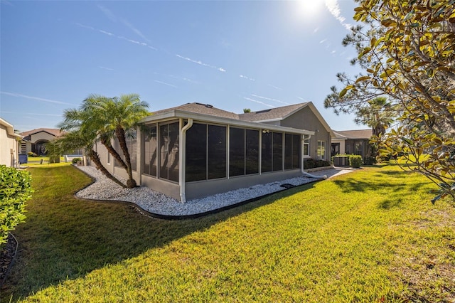 rear view of house featuring a sunroom and a lawn