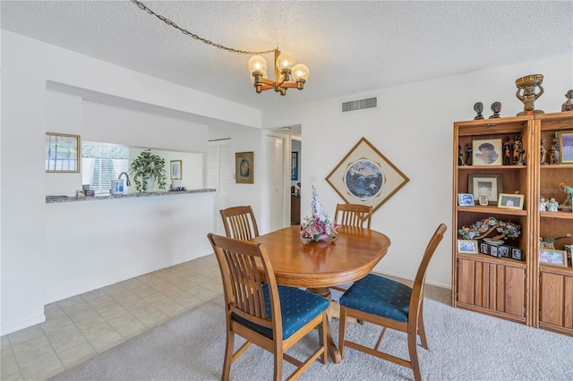 carpeted dining area with a textured ceiling and a chandelier