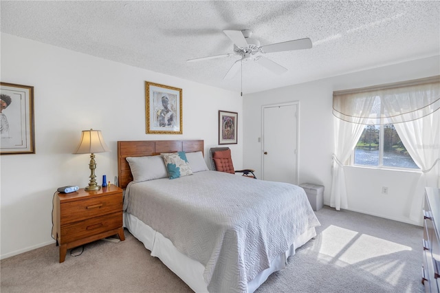 carpeted bedroom featuring ceiling fan and a textured ceiling