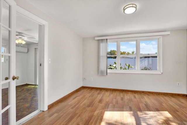 unfurnished room featuring a wall unit AC, ceiling fan, and light wood-type flooring