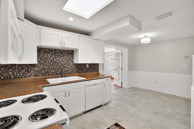 kitchen with tasteful backsplash, sink, white cabinets, and white appliances