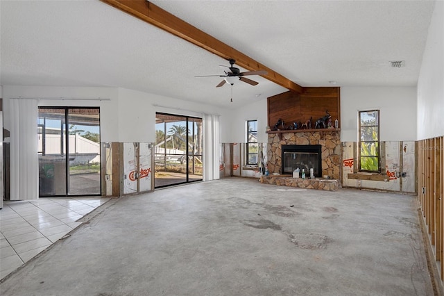 unfurnished living room with a textured ceiling, lofted ceiling with beams, and a stone fireplace