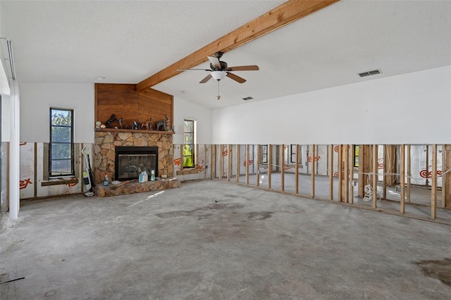 unfurnished living room with a textured ceiling, ceiling fan, concrete floors, a fireplace, and vaulted ceiling with beams