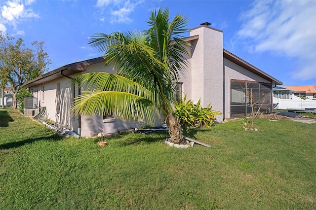 view of property exterior with a yard, central air condition unit, and a sunroom