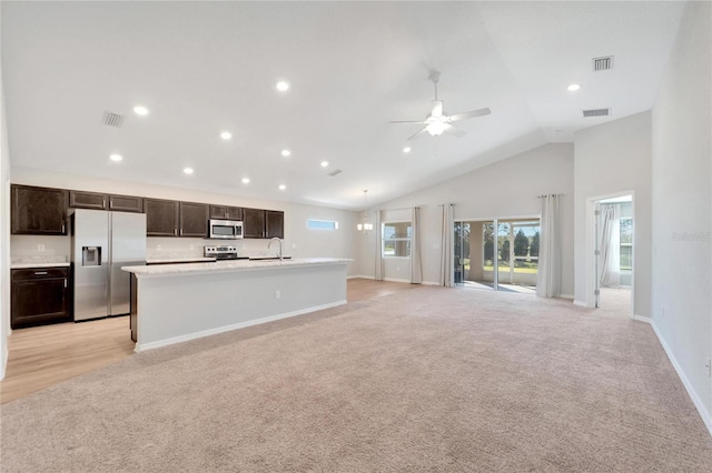 kitchen with a center island with sink, high vaulted ceiling, light colored carpet, and appliances with stainless steel finishes