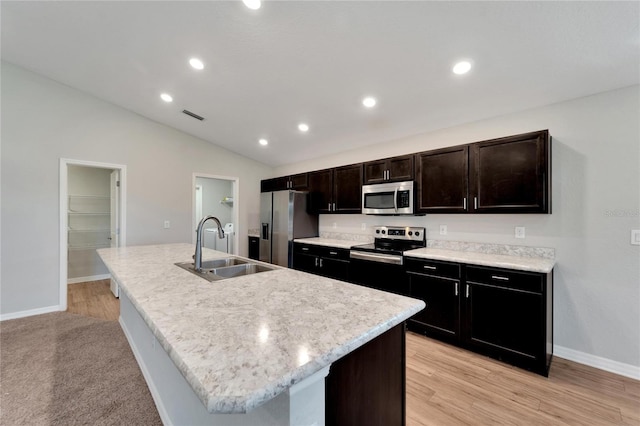 kitchen with light wood-type flooring, stainless steel appliances, sink, a center island with sink, and lofted ceiling