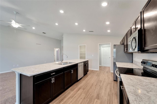 kitchen featuring stainless steel appliances, vaulted ceiling, a kitchen island with sink, sink, and light hardwood / wood-style floors