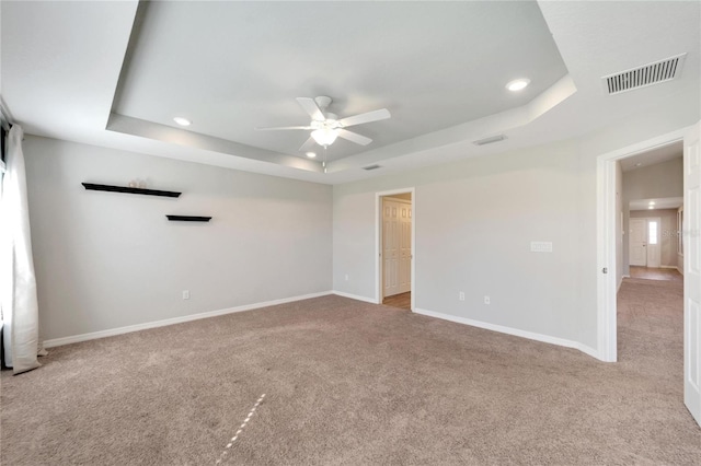 carpeted spare room featuring ceiling fan and a tray ceiling