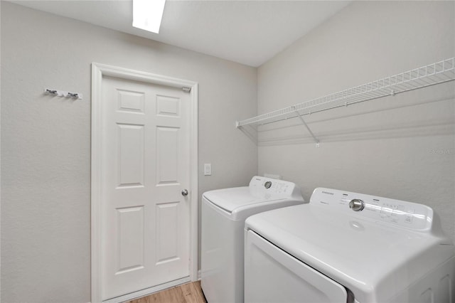 laundry room with light hardwood / wood-style floors and washer and clothes dryer