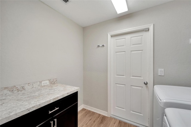 clothes washing area featuring cabinets, separate washer and dryer, and light hardwood / wood-style floors