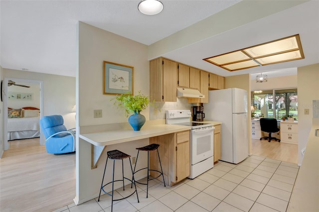 kitchen featuring light brown cabinets, white appliances, light tile patterned floors, kitchen peninsula, and a chandelier