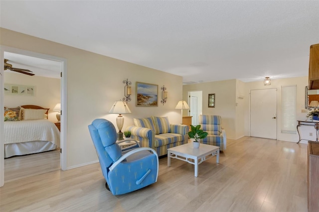 living room with ceiling fan, a textured ceiling, and light hardwood / wood-style flooring