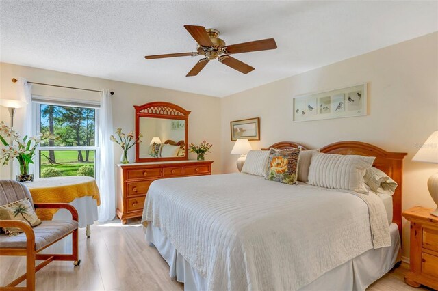 bedroom featuring ceiling fan, light wood-type flooring, and a textured ceiling