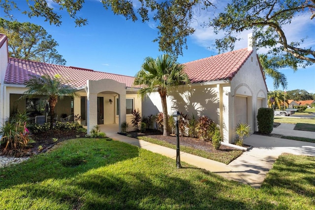 mediterranean / spanish-style home featuring a front yard and a garage