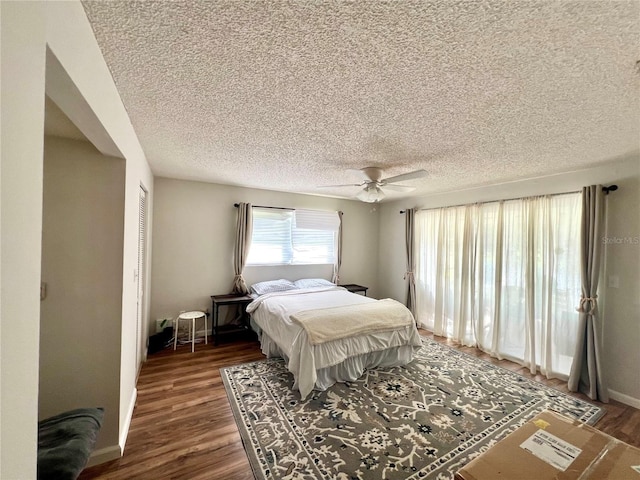 bedroom with ceiling fan, dark wood-type flooring, and a textured ceiling