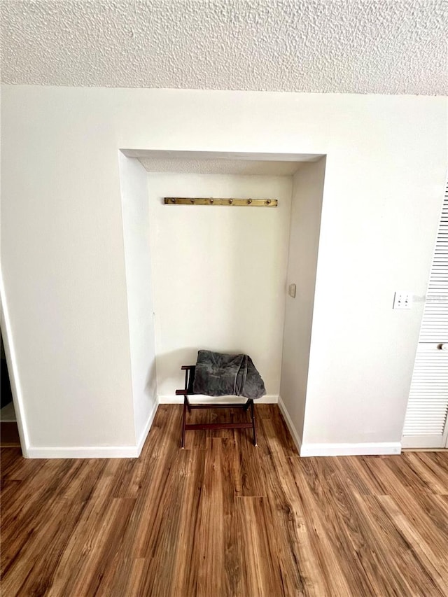 unfurnished room featuring wood-type flooring and a textured ceiling